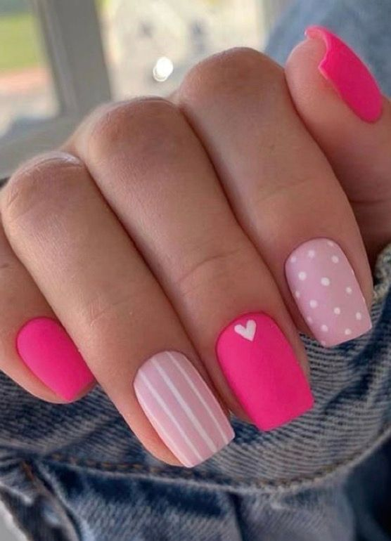 Hot pink and light pink nails with polka dots, stripes, and heart