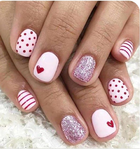 Pink and white Valentine's nails with red hearts, polka dots, stripes, and glitter